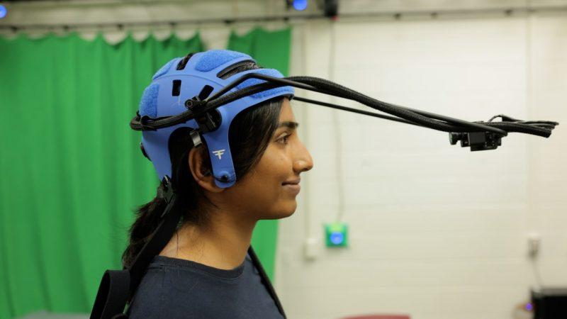 Graduate student Varshita Usem wears a blue helmet with a long harmed camera attached to it.