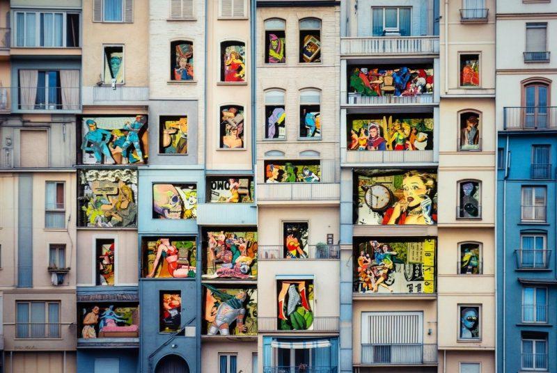 The artist has created what looks to be a concrete building façade, with each window filled with cutout images ranging from a human skull to a superhero to a woman in an evening gown.