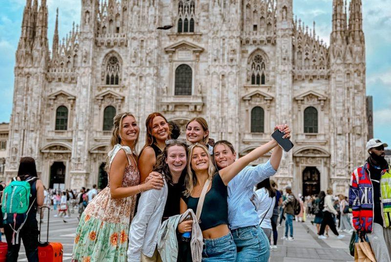 A group of college students smile in front of a castle in Milan, Italy.